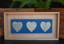 Load image into Gallery viewer, Pale birch floating frame with three loofah hearts on a brilliant blue background
